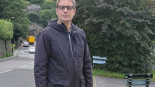 Garth Harkness at one of the grit bin sites, with a steep road behind him